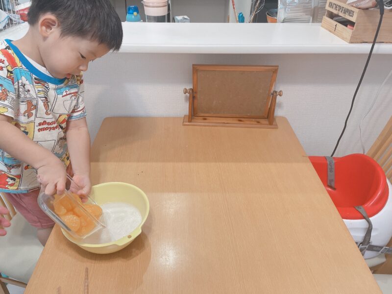 ミルクにみかんを入れる子ども