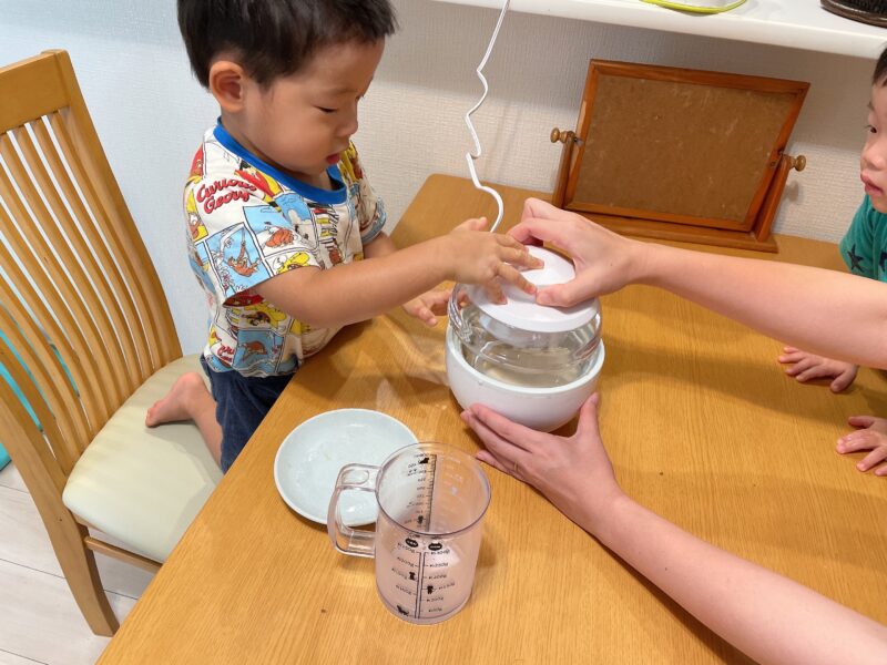 アイスクリームメーカーの蓋を閉める子ども