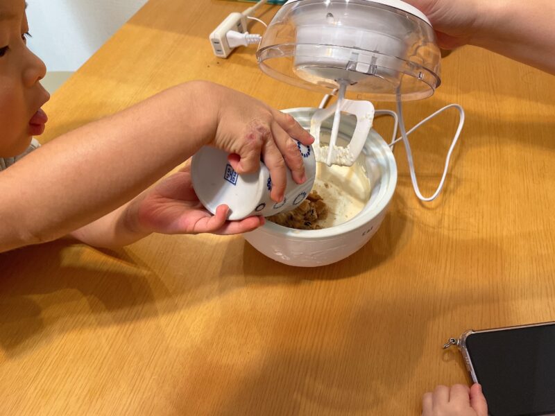 アイスクリームメーカーにチョコクッキーを入れる子ども