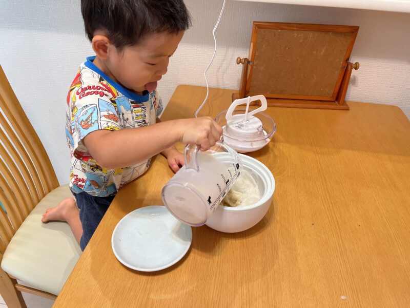 アイスクリームメーカーに牛乳を入れる子ども