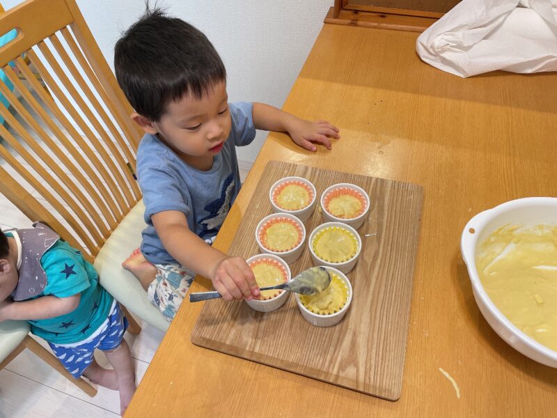 蒸しパンの材料をおかずパックに入れる子ども