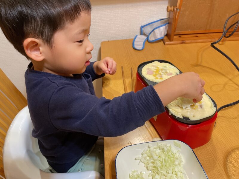 メガたこ焼き器にキャベツを入れる子ども