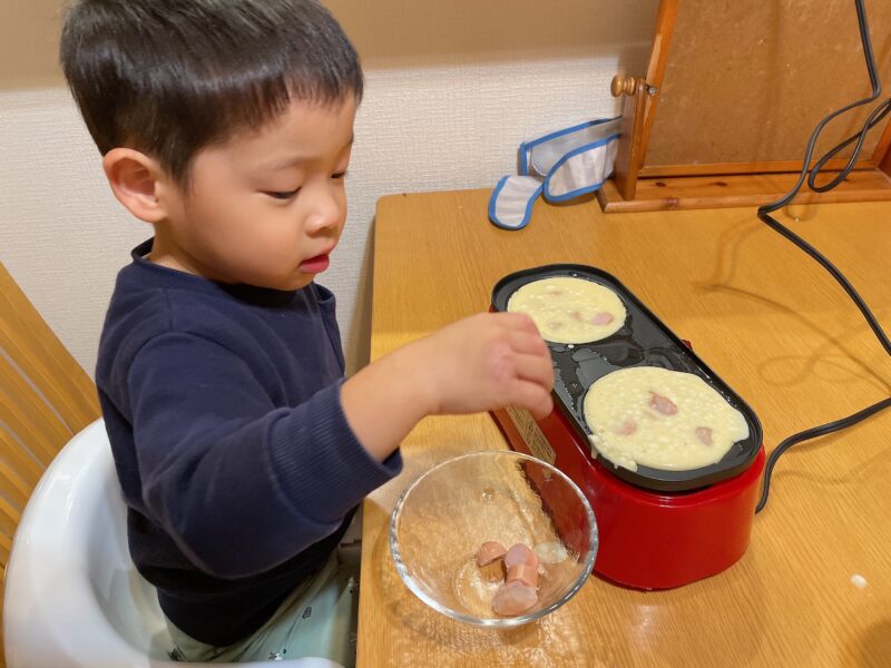 メガたこ焼き器に具材を入れる子ども