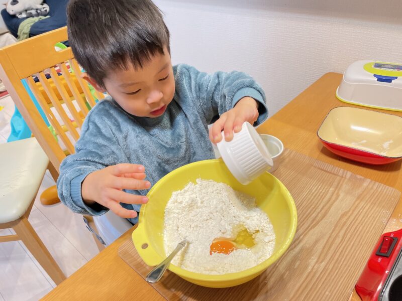 ボウルにホットケーキの材料を入れている子ども