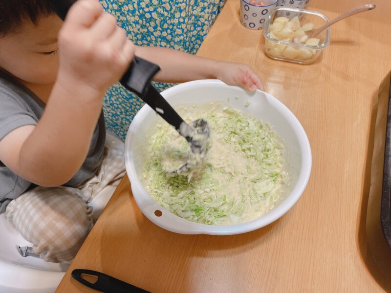 お好み焼きの生地とキャベツを混ぜる子ども