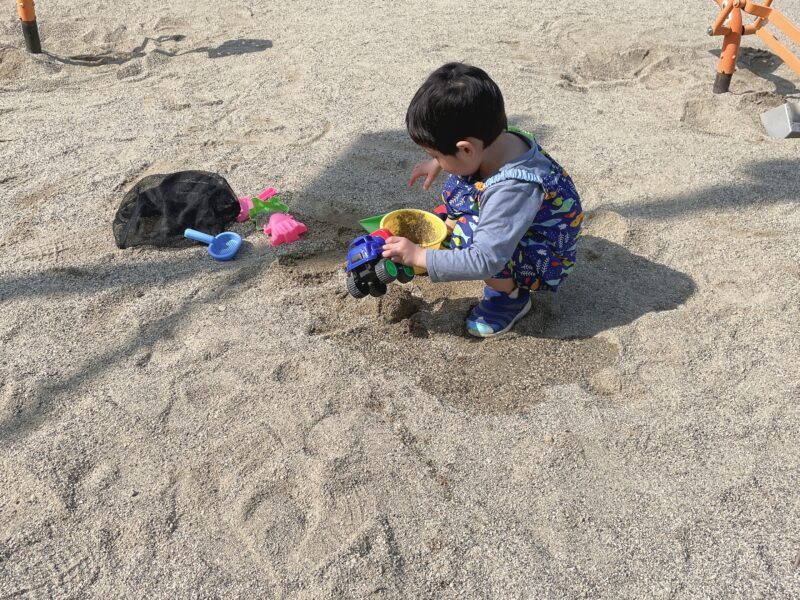 砂場着を着た子どもが砂場で遊んでいる