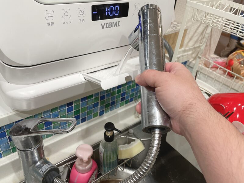 キッチンの蛇口から食洗機に水を入れている