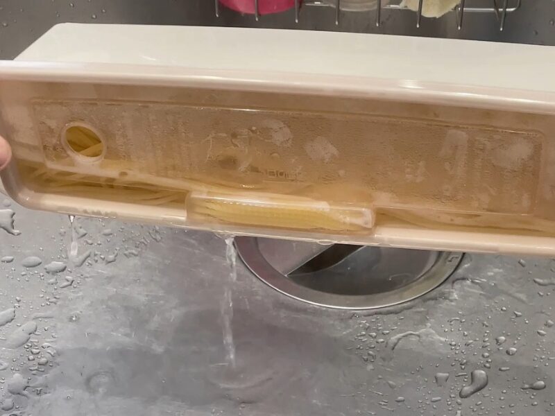 電子レンジ調理容器に入った水を切っている